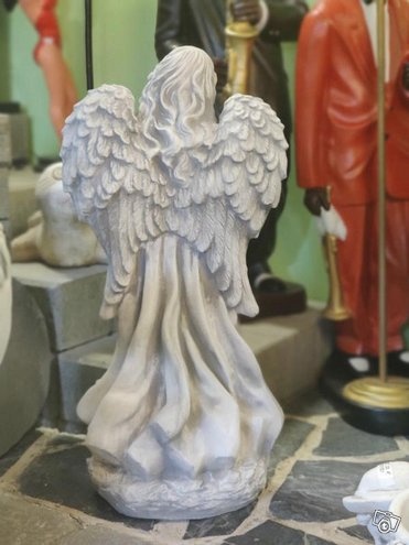 Enkelipatsas, enkeli seisoo jalustalla, kuvattu takaa